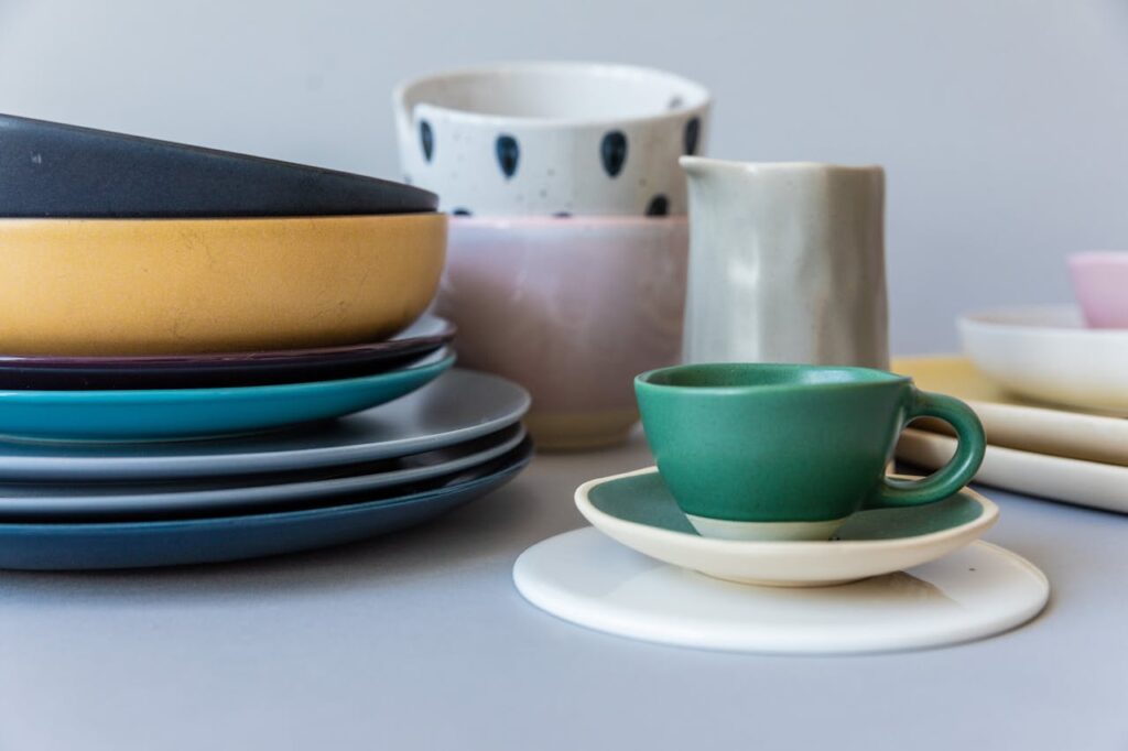 A vibrant collection of ceramic dishes and cups, stacked on a soft background, perfect for kitchen aesthetics.