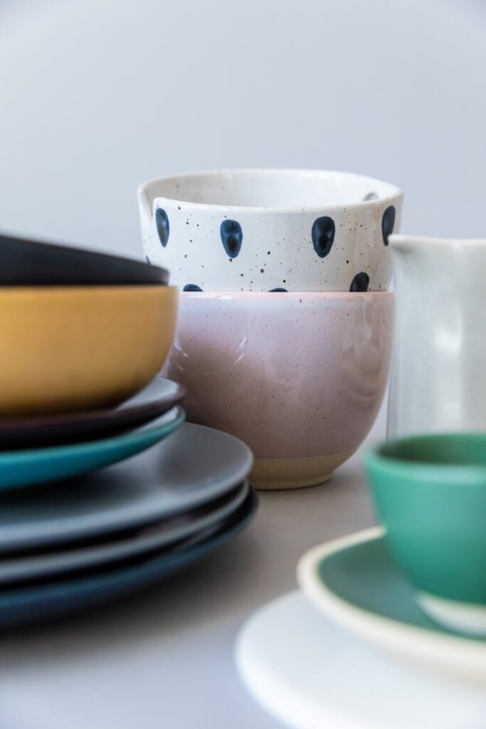 Artistic stack of colorful ceramic dishware and mugs photographed indoors.
